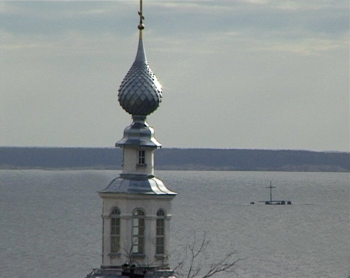 Bell-tower of cathedral of Dormition of the Theotokos and memorial cross on the ground flooded Krivozersky monastery