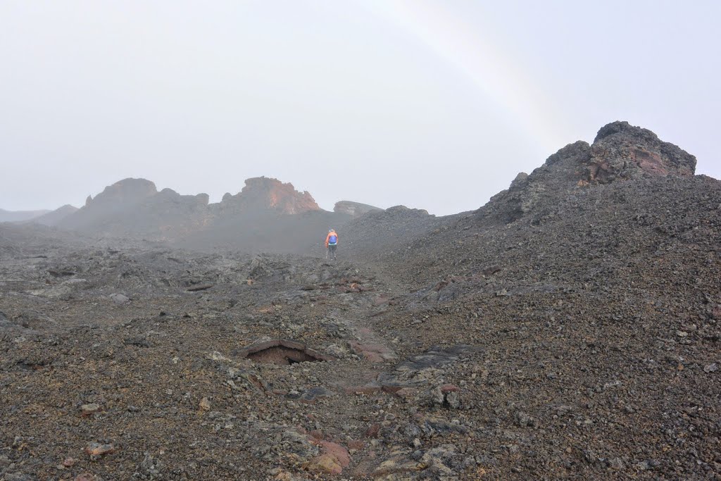 2014-05-01 A hiker by some ancient lava fissure under rainbow.