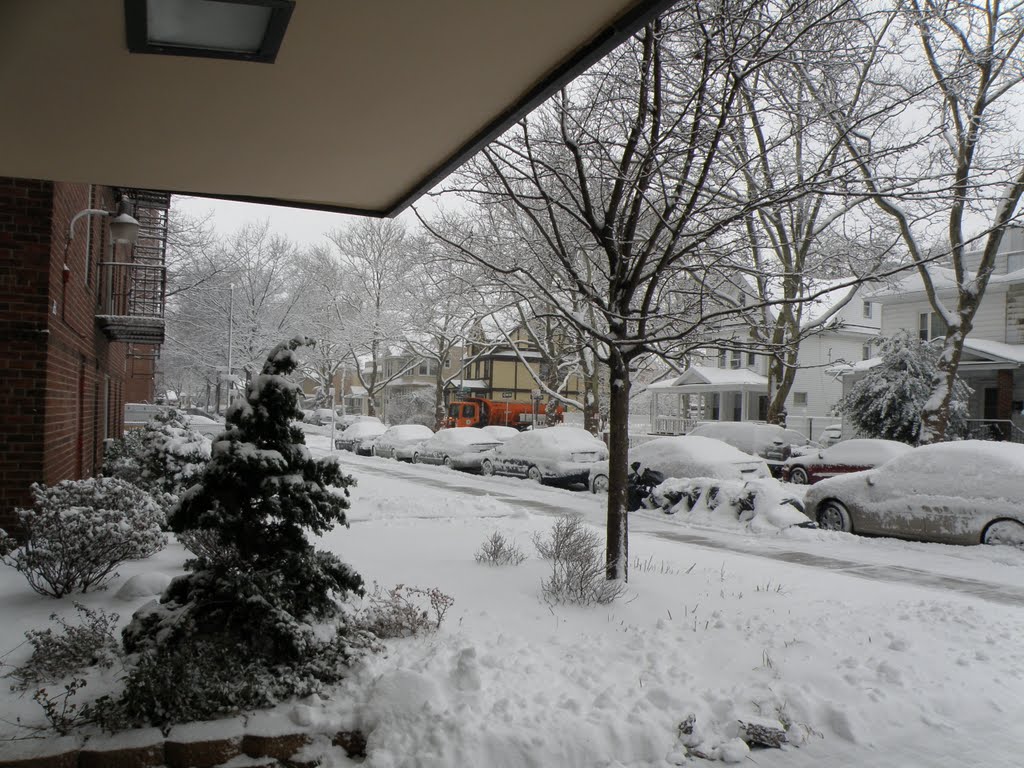 Red Truck spraying the salt on the streets on a beautiful snowy day.Snow is covering the christmas tree and the entire street.