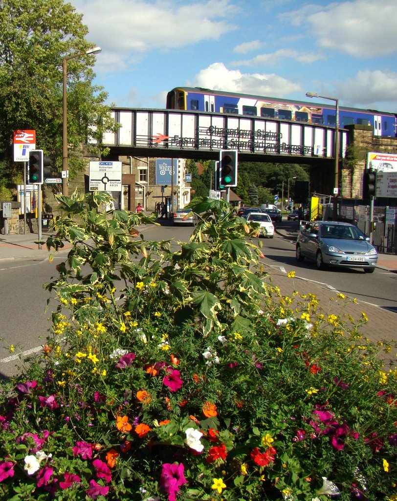 Looking over flower display towards train on the bridge leaving Chapeltown Station, Sheffield S35